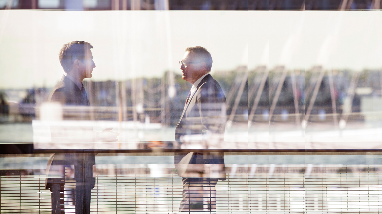 Zwei Männer reden draußen hinter einer Glasscheibe
