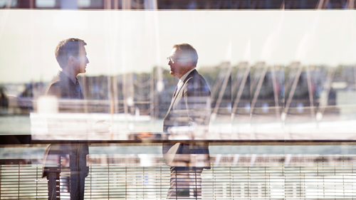 two men talking outside behind window