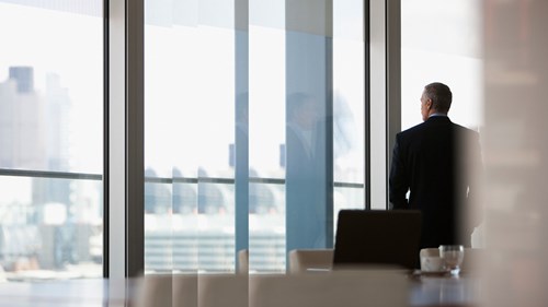 Mann im Konferenzraum vor Fensterfront Dawn Raid
