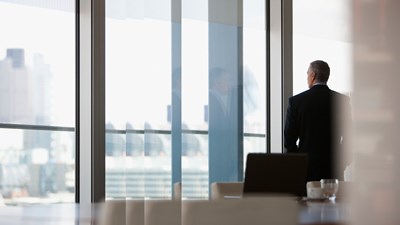 Mann im Konferenzraum vor Fensterfront Dawn Raid
