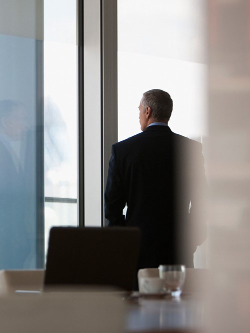 Mann im Konferenzraum vor Fensterfront Dawn Raid