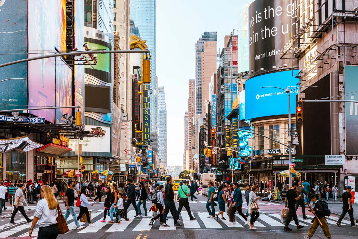 Menschen überqueren Zebrastreifen in New York zwischen Wolkenkratzern