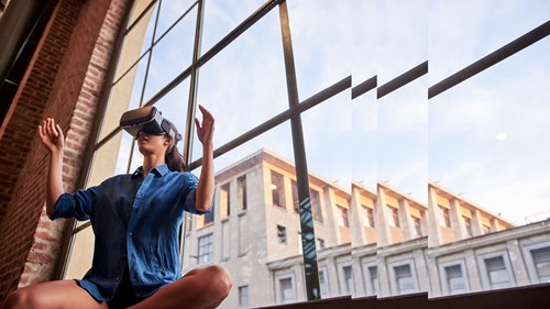 Frau mit Virtual Reality Brille sitzend vor Fensterfront Innovation