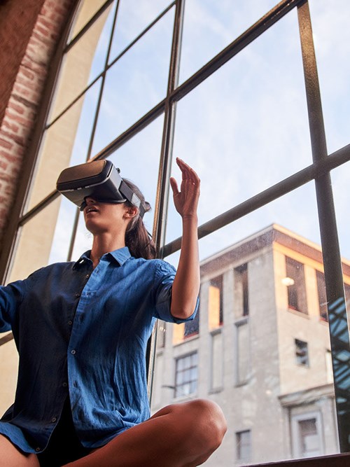 Frau mit Virtual Reality Brille sitzend vor Fensterfront Innovation