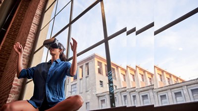 Woman sitting in front of window wall with virtual reality device innovation